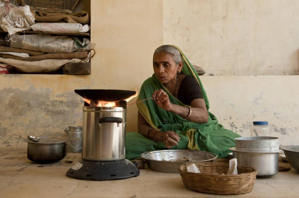 Leela Ben cooks food on her cookstove at her house